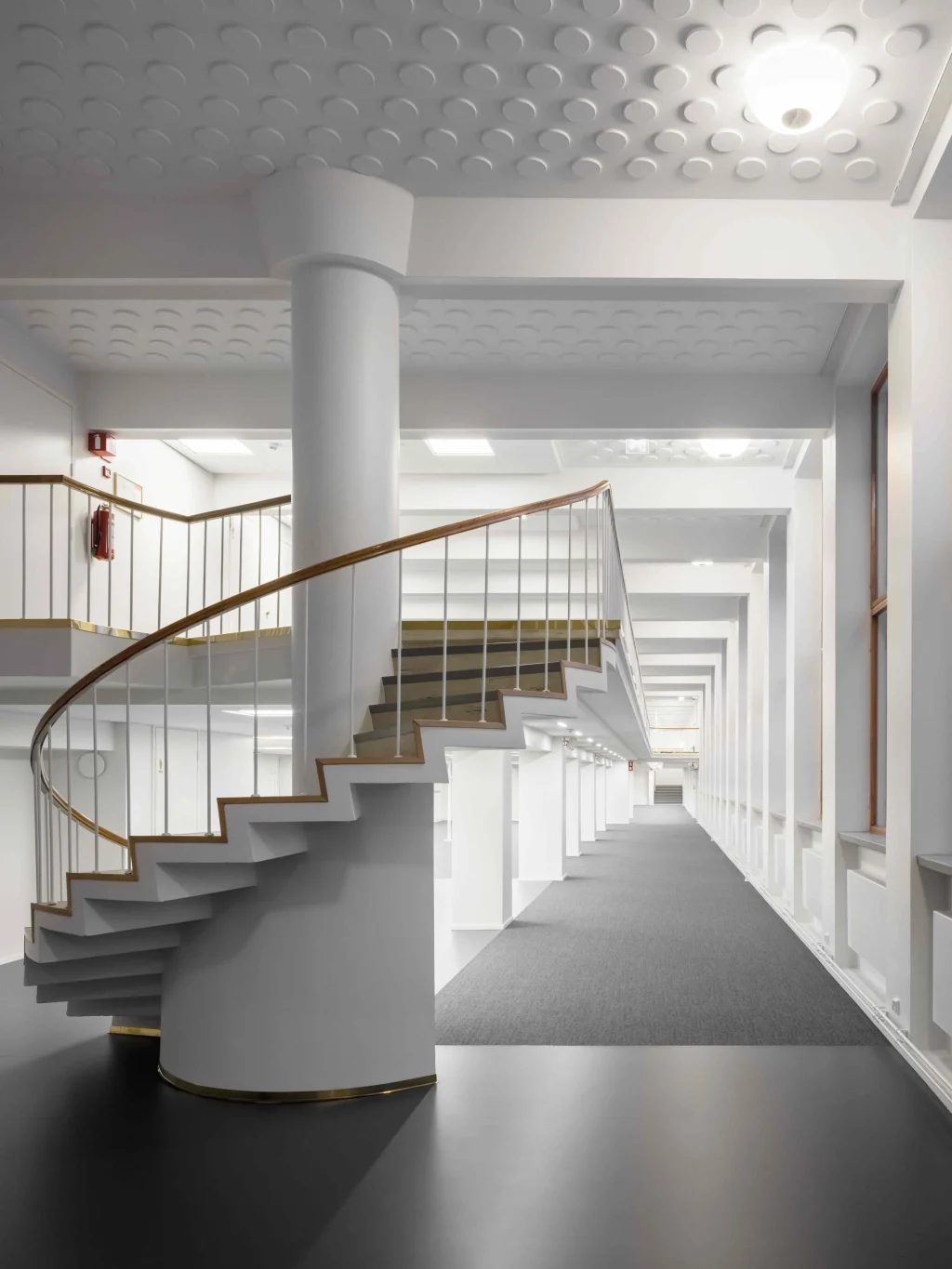 Runeberginkatu 14–16 portaikko – kaareva klassinen portaikko, korkea tila ja ajaton arkkitehtoninen yksityiskohta Töölön toimitilassa.